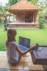 女孩手持手机, 咖啡杯与笔记本电脑在花园门廊