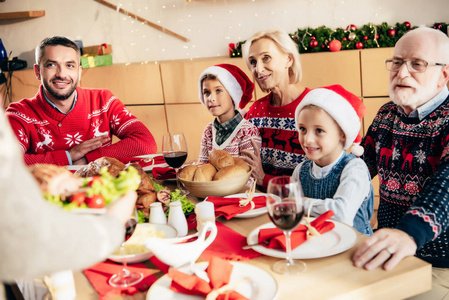 在餐桌上与快乐家庭一起吃圣诞大餐的妇女的裁剪图像