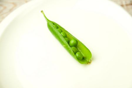 原生大白芸豆和蓝紫猩红豆在棕盘子上, 叶子和豆荚在竹木表面上