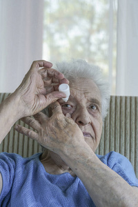 一个老年妇女自己用眼滴