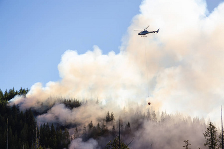 直升机在炎热的阳光明媚的夏日里与 Bc 森林大火搏斗。靠近爱丽丝, 温哥华北部岛屿, 加拿大不列颠哥伦比亚省