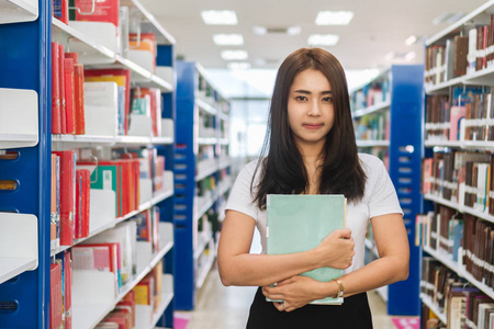 大学图书馆教育和研究理念中的年轻亚裔女学生的画像和看照相机