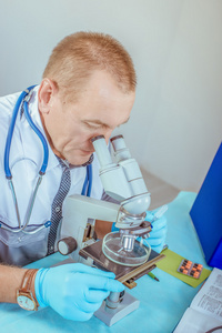 一位男医生用在实验室显微镜的肖像