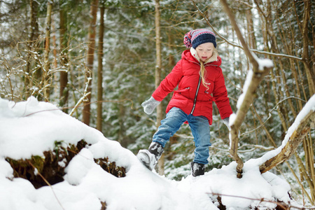 可爱的小女孩在美丽的冬季森林乐趣。快乐的孩子在雪地里玩耍。儿童冬季活动