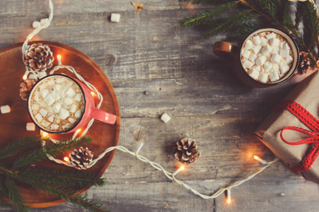顶视图的热可可和棉花糖与圣诞灯仿古木制的桌子上。舒适的冬天的家居理念