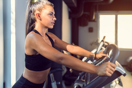 在健身房的固定自行车上做有氧运动的女人