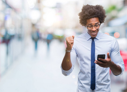 美国黑人商业人短信使用智能手机在孤立的背景下尖叫着自豪和庆祝胜利和成功非常兴奋, 欢呼的情绪