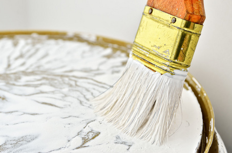 油漆刷白色油漆的木柄。在工作中的油漆工具。维修及装修工程