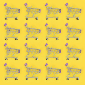 购物成瘾, 购物爱好者或者是购物狂的概念。许多小的空购物车在柔和的彩色纸张背景上执行图案。平躺组合, 顶部视图