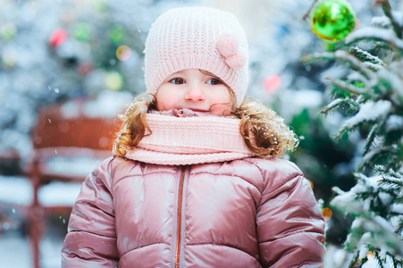 圣诞节和冬天的肖像快乐的3岁的蹒跚学步的孩子女孩在雪地上漫步在圣诞假期与树木的背景装饰