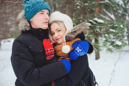 快乐的年轻情侣漫步在白雪皑皑的冬季森林, 有乐趣和拥抱。户外活动冬季假期