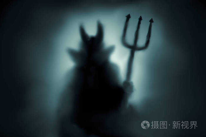 可怕的魔鬼剪影背后的冰冻玻璃和在薄雾与背光