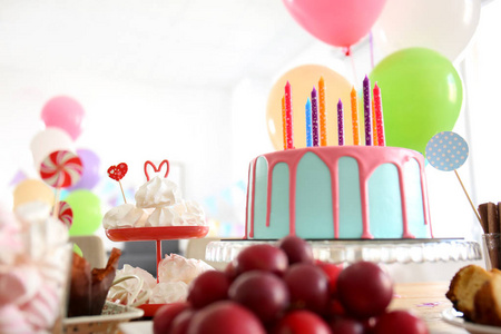 美丽的生日蛋糕与蜡烛和不同的糖果桌上