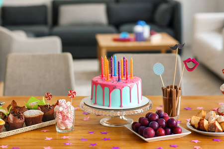 美丽的生日蛋糕与蜡烛和不同的糖果桌上