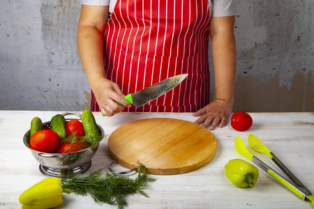 女人穿着红色围裙, 厨房里拿着刀子。烹饪