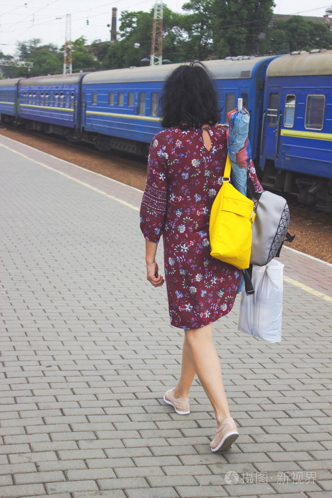 一个带袋子的女人走在站台上的火车上