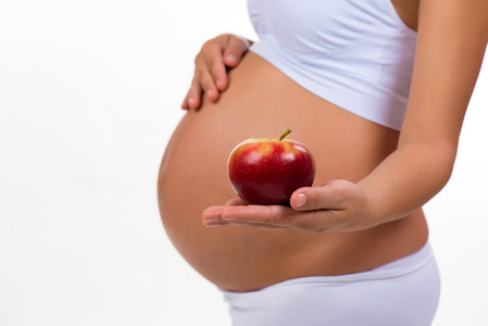 孕妇的肚子和苹果的特写镜头。维生素和怀孕期间的健康食品