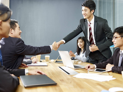 两位亚洲企业高管握手谈判桌照片