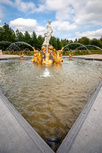 金色的水随地吐痰天鹅和神话般的女性希腊雕像, 在一个宫殿花园的雕刻喷泉