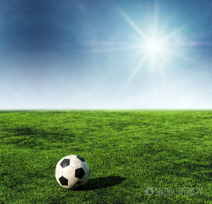 足球在足球场的绿色草地上的阳光照在蓝天上