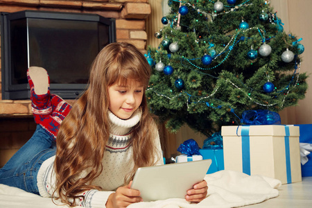 快乐的少女与平板电脑附近的圣诞树