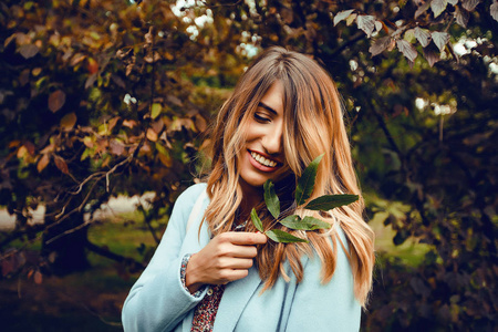 秋季公园穿蓝大衣的快乐年轻女子户外画像