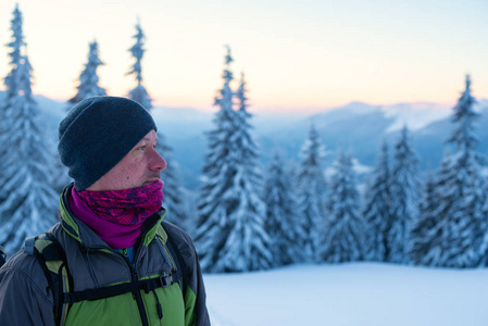 探险家站在日落时覆盖着积雪的巨大松树中。史诗般的冬季旅行在山上