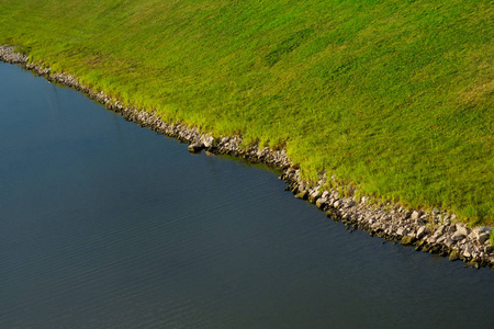 河岸边明亮的绿色的草和石头关闭照片