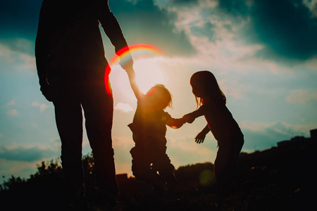 父亲与两个女儿走在日落时照片