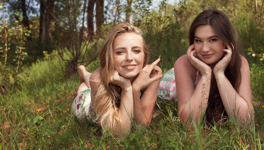 在夏天夏天白天躺在草地上的两个女孩朋友