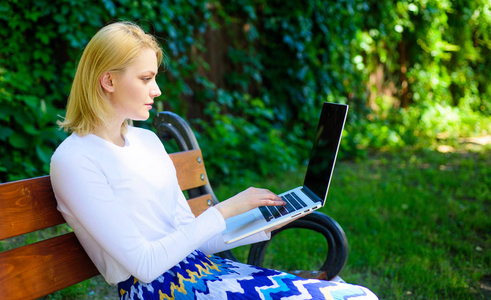 远程作业浏览顶级自由职业者远程工作机会。妇女与笔记本电脑作品户外绿色自然背景。女自由职业者在公园工作。女孩坐板凳与笔记本寻找新的