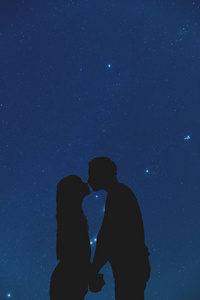 星光灿烂的天空下的一对年轻情侣的剪影