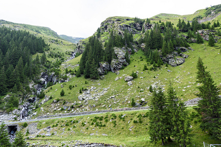 绿色山峰，一条小河和罗马尼亚 fagaras 山区道路的照片