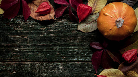 感恩节快乐。南瓜和落叶在黑暗的木质背景。秋季蔬菜和季节性装饰品。秋天收获和假日寂静的生活