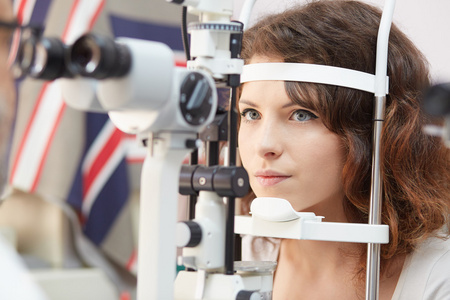 漂亮的女人望眼试验机在眼科医生的实验室里的浓度