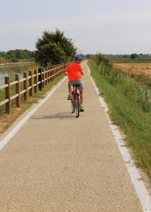 男孩骑在威尼斯泻湖附近的自行车道上