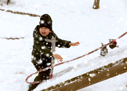 可爱的小滑稽的男孩有乐趣在雪, 室外在降雪期间