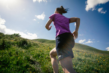 年轻健身女子小径赛跑者在草原上奔跑
