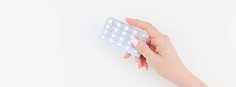 女人手用粉彩指甲抛光在白色背景与复制空间隔离的水泡药片。长宽横幅为女性美丽博客社交媒体。女性保健理念