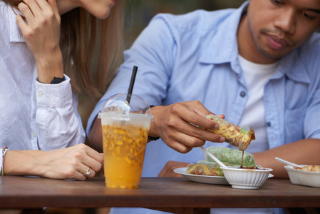 在户外咖啡馆与女友共进午餐时, 男人蘸着弹簧卷成酱汁。