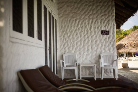 马尔代夫花园小屋甲板上的两个木制休息室椅和两把扶手椅