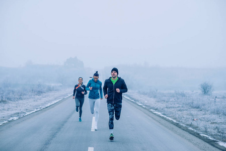 三名运动员在冬天的露天路上奔跑的镜头照片