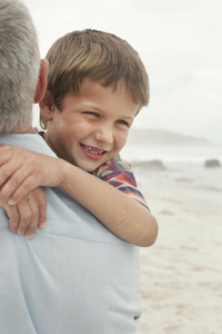 父亲在海滩上抱着快乐的男孩