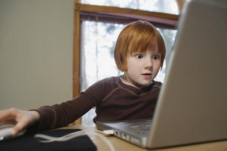 惊讶的女孩在家里用笔记本电脑