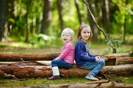 两个小妹妹坐在一根大圆木上