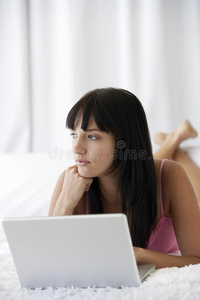 躺在床上拿着笔记本电脑的体贴女人