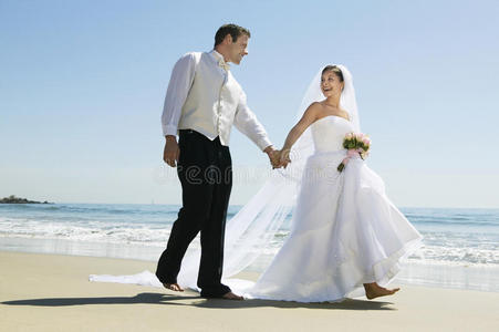 新婚夫妇在海滩上散步时手牵着手