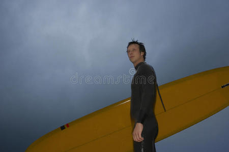 自信的人带着冲浪板，望着阴云密布的天空