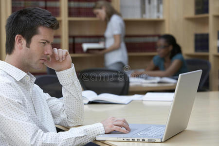 主管在办公室里和同事一起使用笔记本电脑