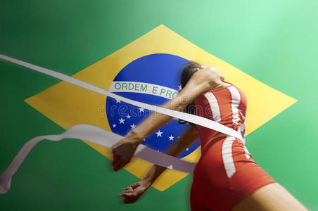 在巴西国旗上冲破终点线胶带的赛跑运动员